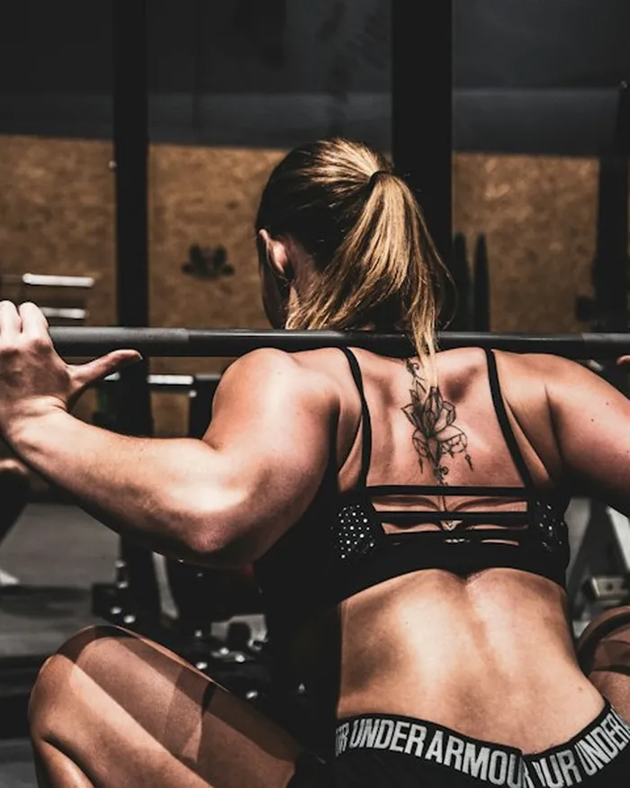 Mulher fazendo agachamento com barra na academia